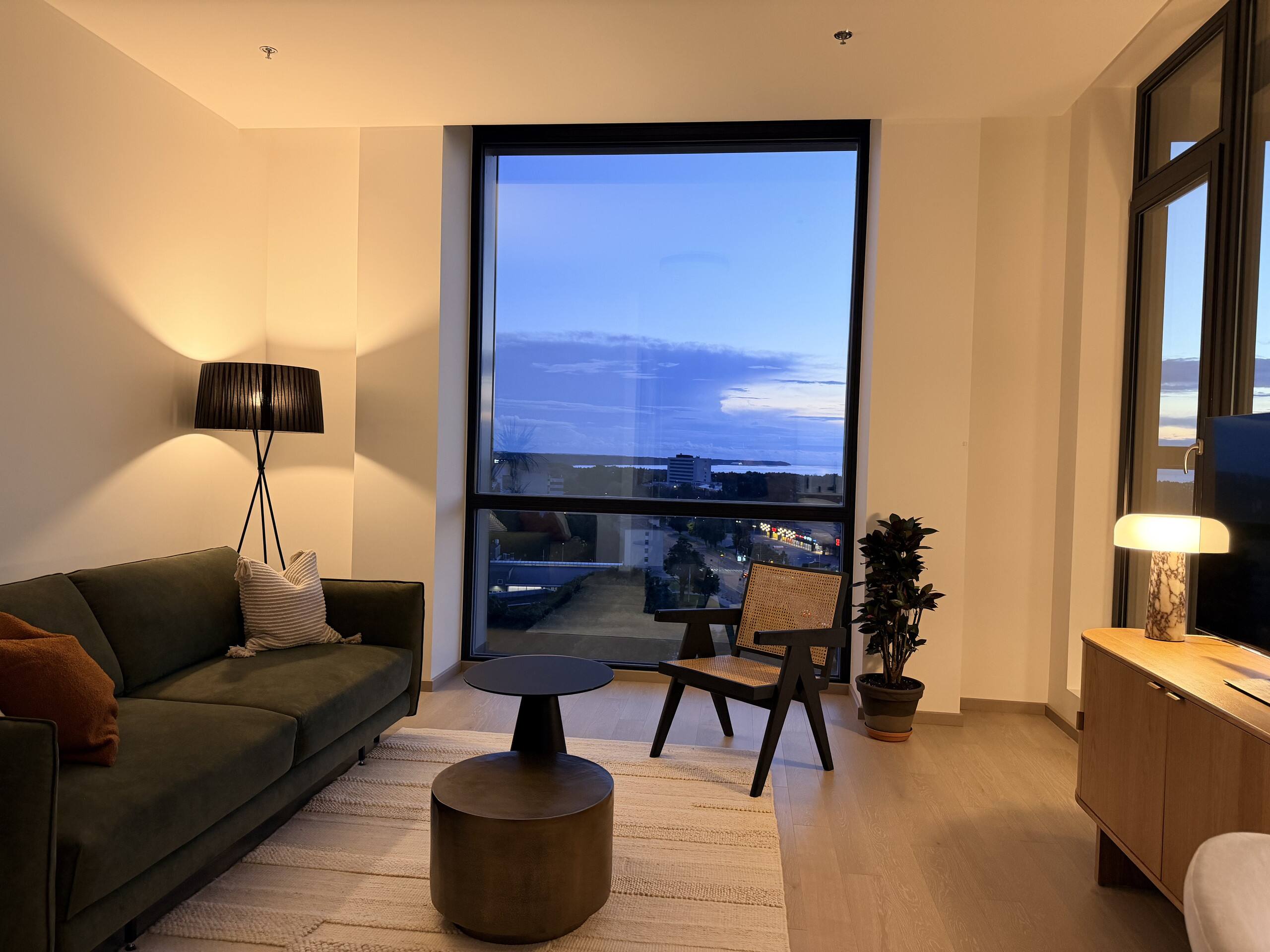 The living room of the apartment, looking out through floor-to-ceiling windows toward the sea.